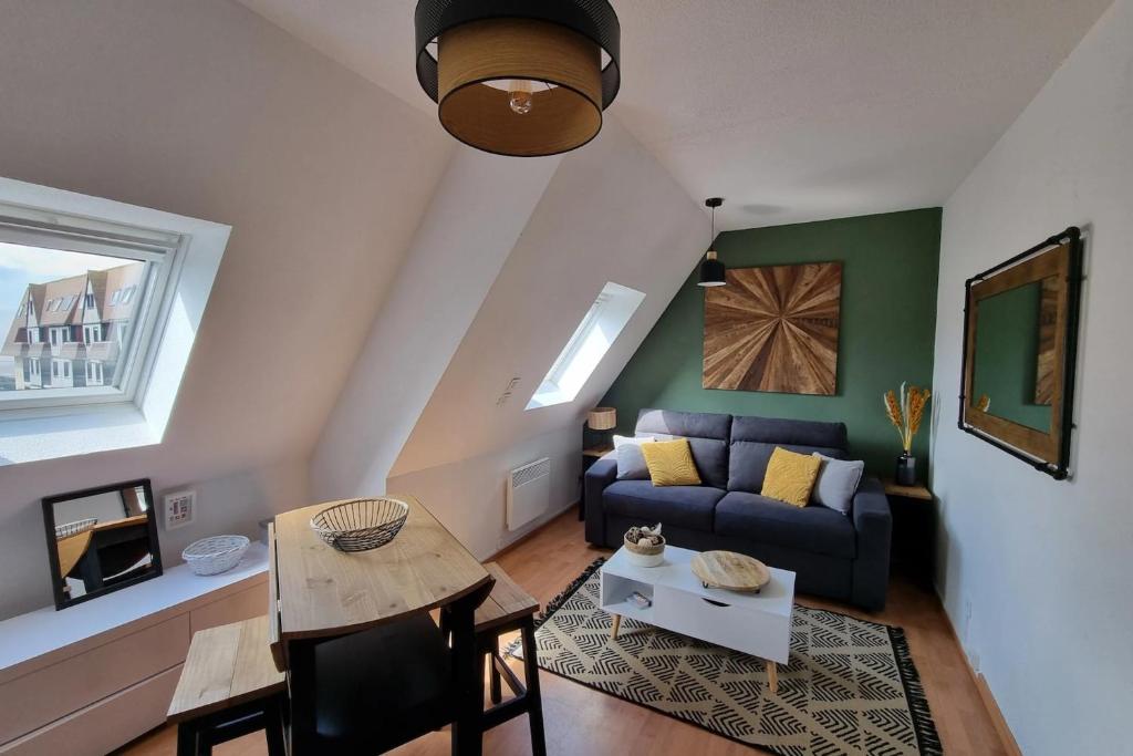 a living room with a couch and a table at Studio cocooning petite vue mer in Cabourg