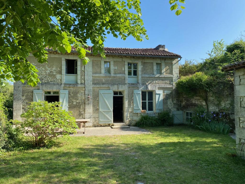 ein altes Steinhaus mit einer Bank im Hof in der Unterkunft Maison de charme avec piscine in Orches