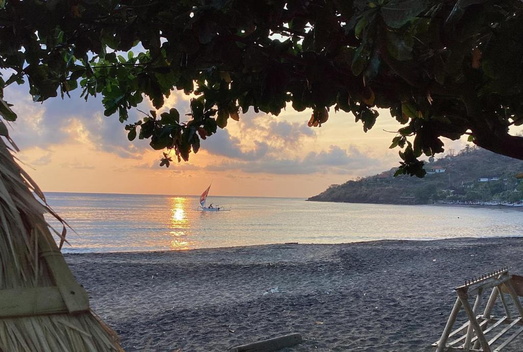 une personne fait de la planche à voile sur la plage au coucher du soleil dans l'établissement Bintang Beach Villa, à Amed