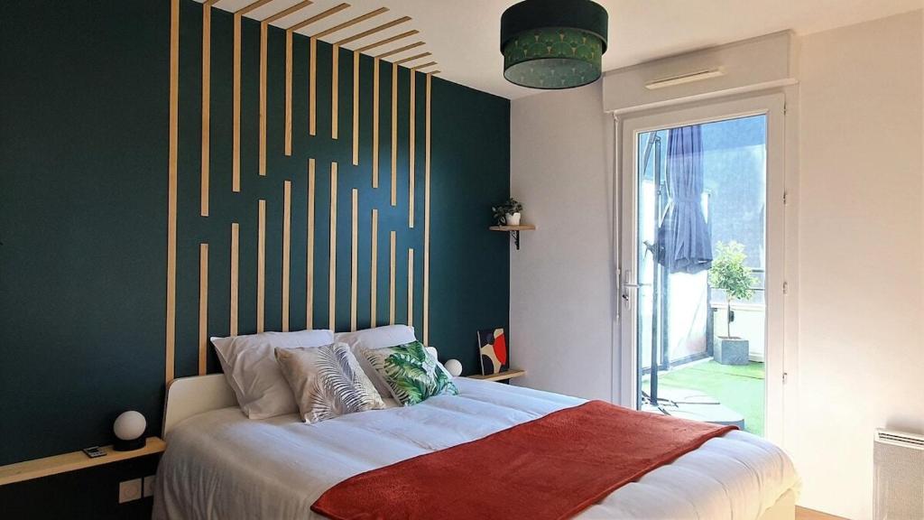 - une chambre avec un grand lit et un mur vert dans l'établissement Logement moderne et lumineux Terrasse et Parking, à Caen