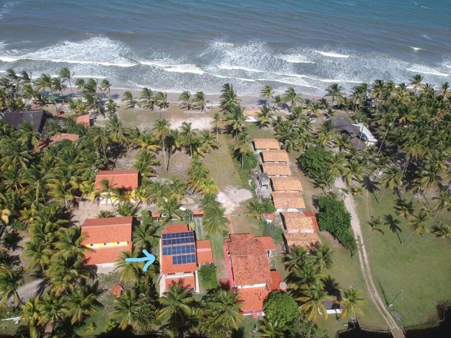 an aerial view of a resort with palm trees and the ocean at Casa de praia pé na areia: nos braços da natureza. in Ilhéus