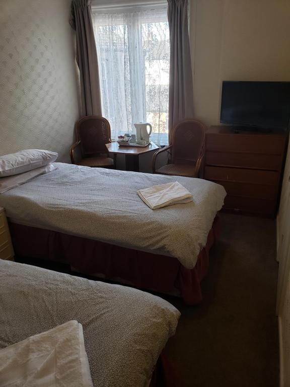 a room with two beds and a table and a window at Nevada Hotel in Blackpool