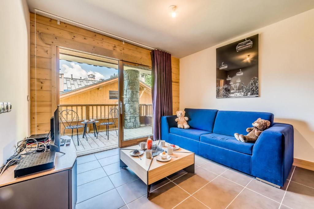 uma sala de estar com um sofá azul e uma mesa em Résidence Les Balcons EtoilÉs - 2 Pièces pour 4 Personnes 194157 em Champagny-en-Vanoise