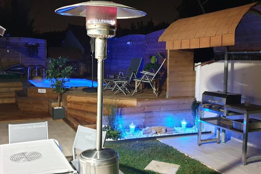 une terrasse avec un foyer extérieur, une table et des chaises dans l'établissement La Petite maison sympa avec piscine et bbc JO 2024, à Saint-Fargeau