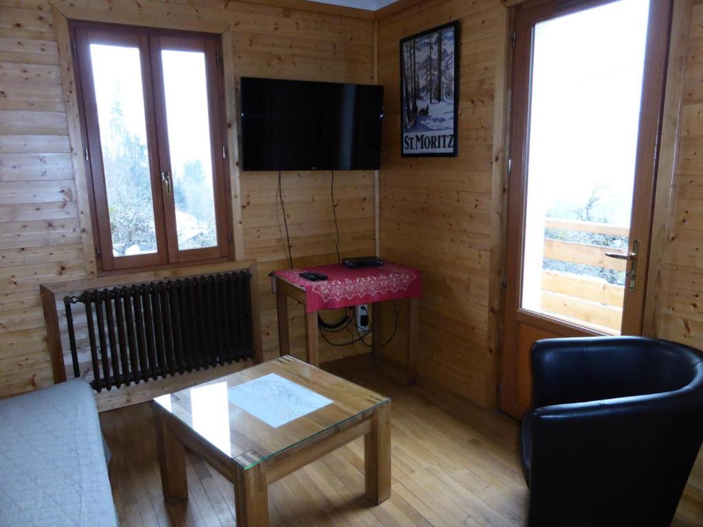 un salon avec une table et une télévision au mur dans l'établissement Chalet Pylone - Chalet Pylone MAE-5198, à Saint-Gervais-les-Bains