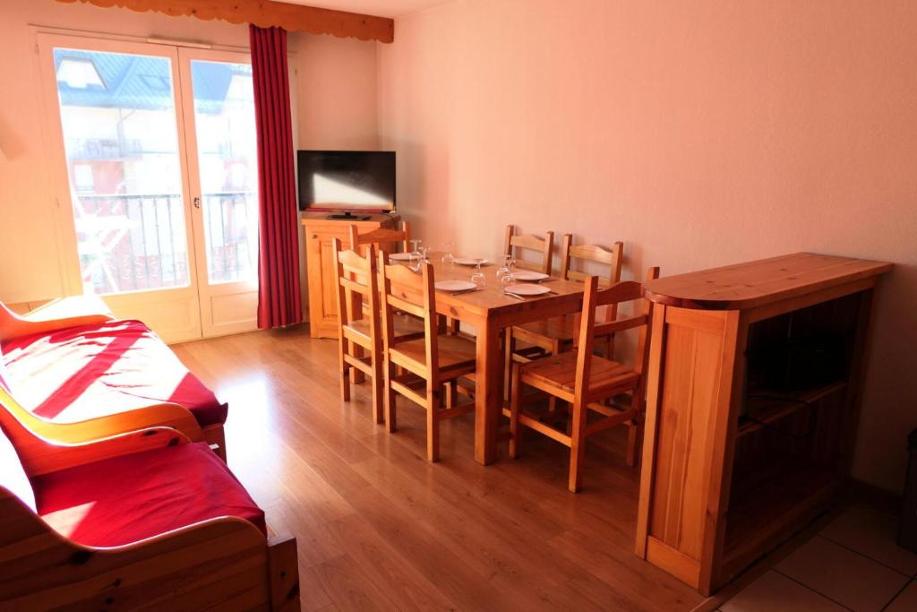 ein Esszimmer mit einem Tisch, Stühlen und einem TV in der Unterkunft Résidence Le Grand Panorama - 2 Pièces pour 6 Personnes 52 in Saint-Gervais-les-Bains
