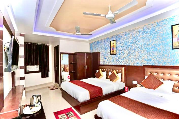 een slaapkamer met 2 bedden en een plafondventilator bij Hotel The Blue rose 500mtr Taj in Tājganj