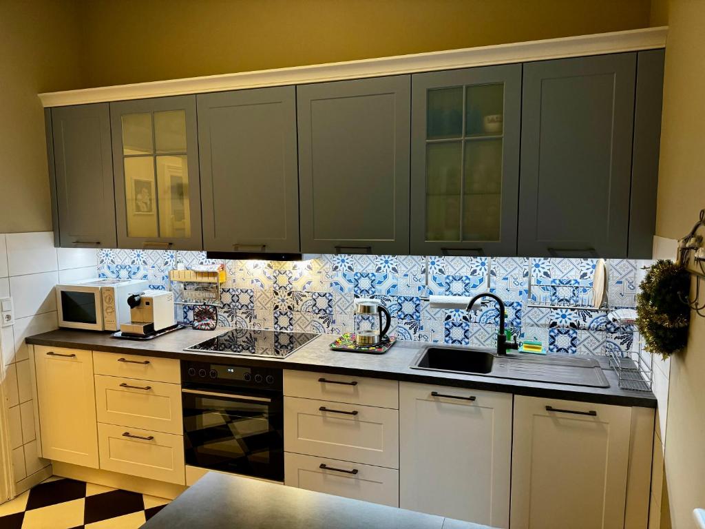 a kitchen with white cabinets and blue and white tiles at Schloss Apartment, Zentrum Baden-Baden in Baden-Baden