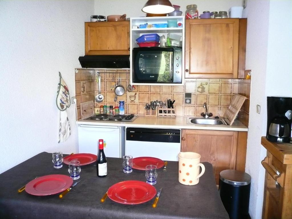 une cuisine avec une table et des plaques rouges. dans l'établissement Résidence Les Granges D'ormaret - Grandes d'Ormaret 16 MAE-5318, à Combloux