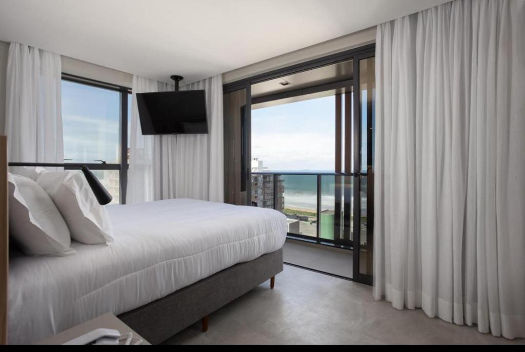 ein Hotelzimmer mit einem Bett und einem großen Fenster in der Unterkunft Não tem vagas mais , o aplicativo tá com bugue e está deixando fazer reserva, porém não tem mais disponibilidade para mais nem um dia nem ano in Itajaí