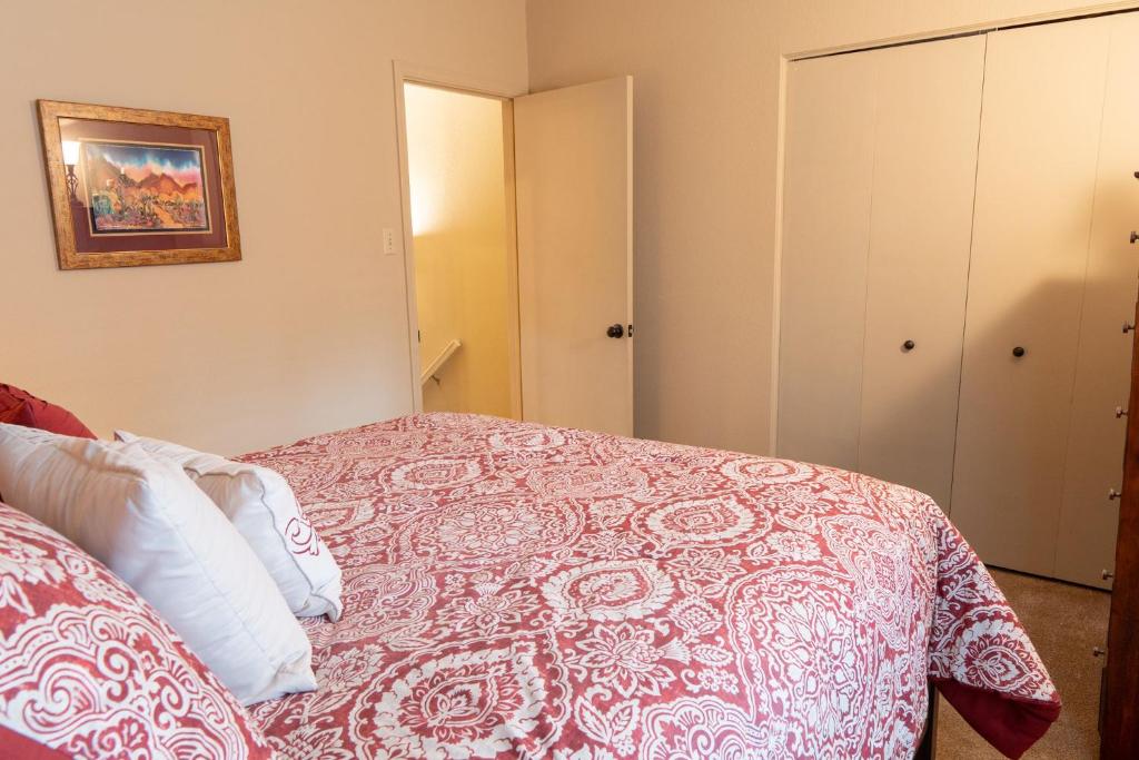 a bedroom with a bed with a red and white blanket at Grisham's View Condo: Central Condo with a Golf Course View! in Ruidoso