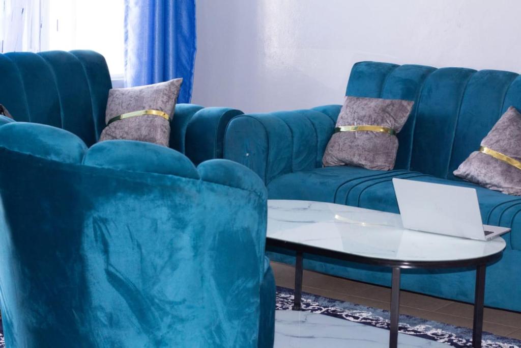 a blue couch and a table with a laptop on it at elegant luxury 2 bedroom mombasa wifi two balconies in Mombasa