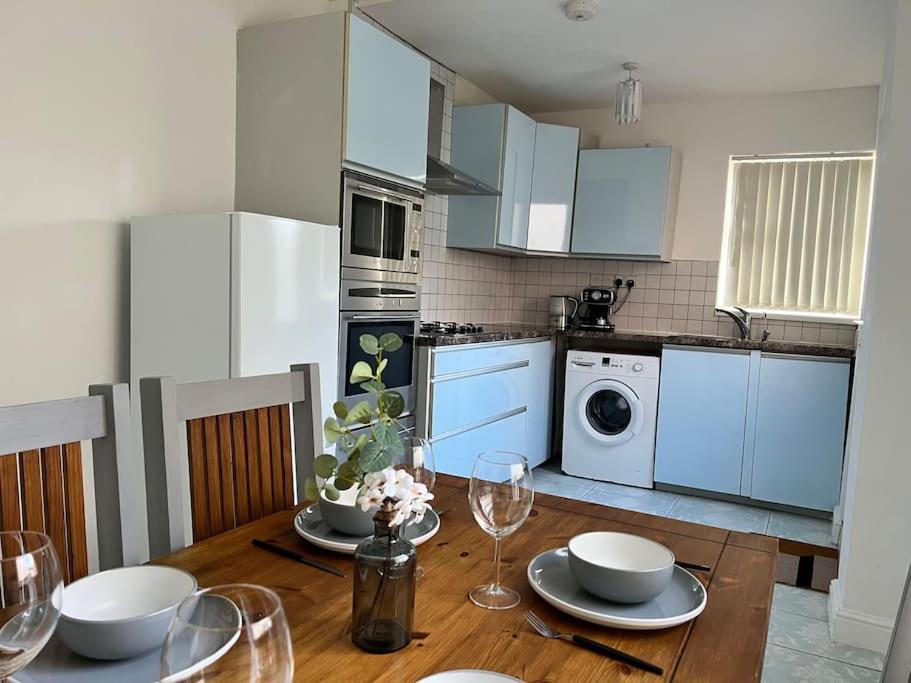 cocina con mesa de madera y copas de vino en One-Bedroom Flat with Parking and Garden, en Birmingham