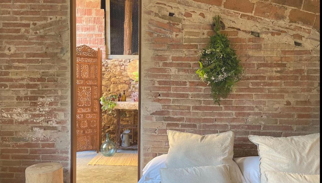 um quarto com uma parede de tijolos e uma cama com almofadas em L'ESTABLE DE CAN TABERNER em Bigues i Riells