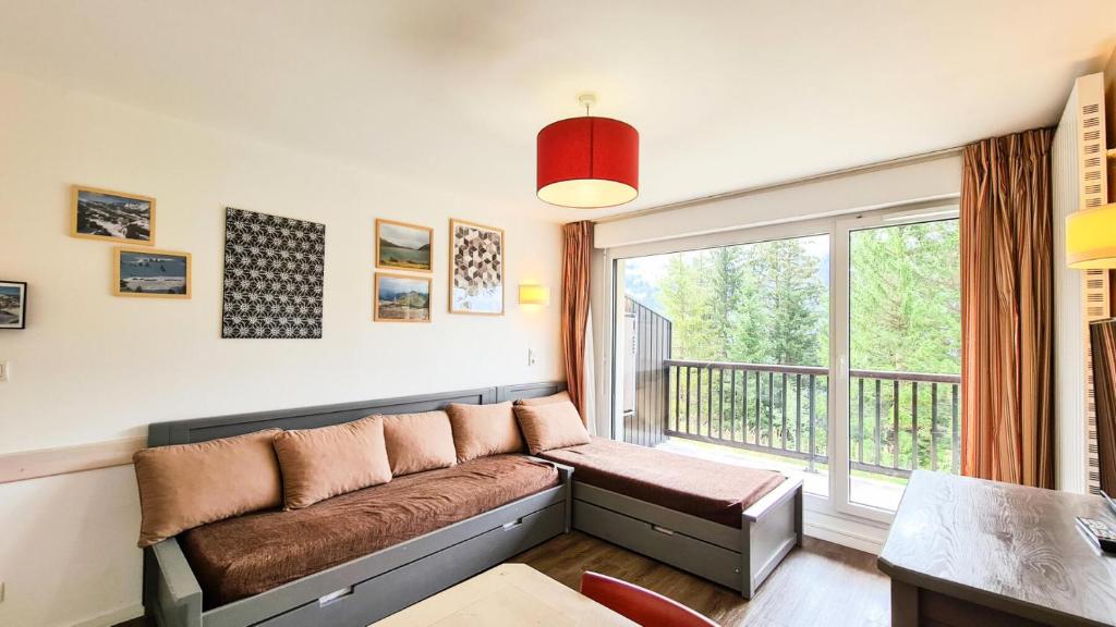 ein Wohnzimmer mit einem Sofa und einem großen Fenster in der Unterkunft Résidence Les Pleiades - 2 Pièces pour 4 Personnes 01 in Flaine