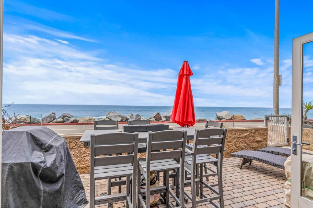 a table with a red umbrella and chairs on the beach at Oceanside Escape in Oceanside
