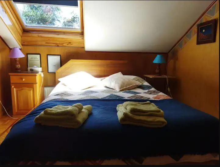Un dormitorio con una cama azul con toallas. en Habitación para dos personas cama matrimonial y Habitación para una persona cama individual en Valdivia
