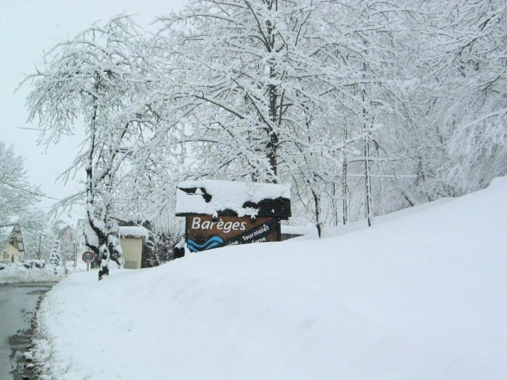 een sneeuwbedekte tuin met een bord voor de bomen bij Résidence Europe - Studio pour 5 Personnes 294 in Barèges