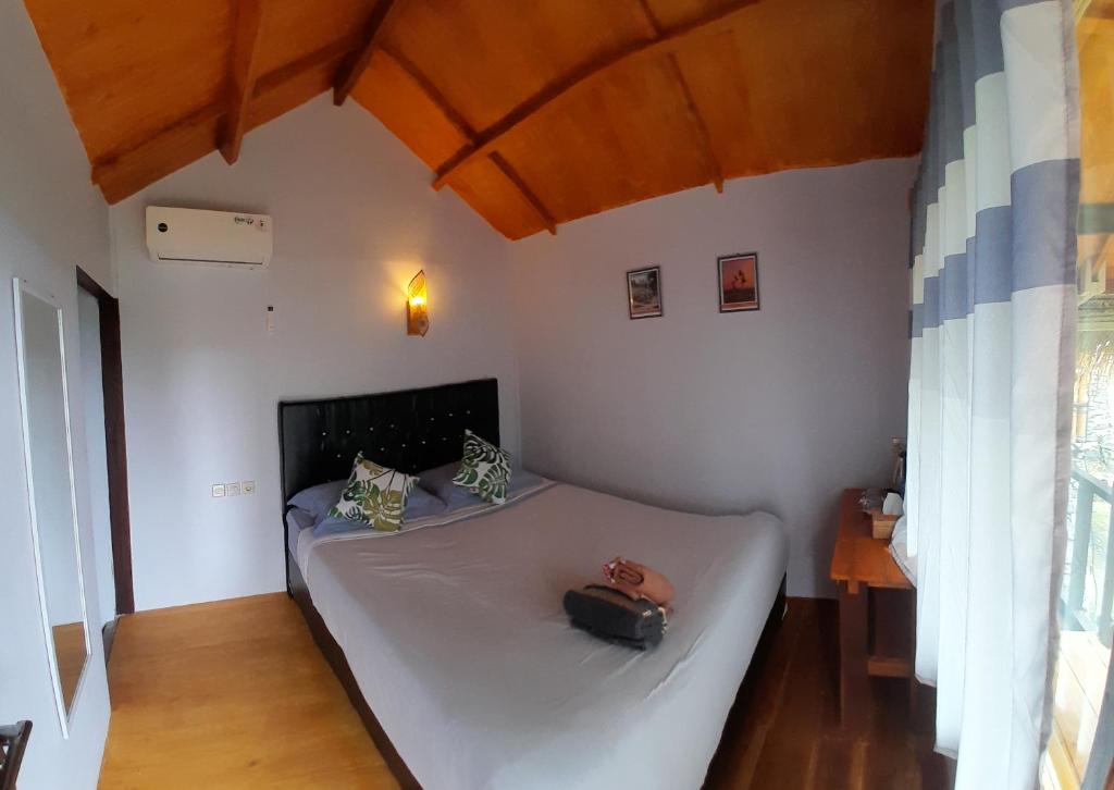 Un dormitorio con una cama blanca con una bolsa. en Poetri Bungalow & Restaurant, en Senaru