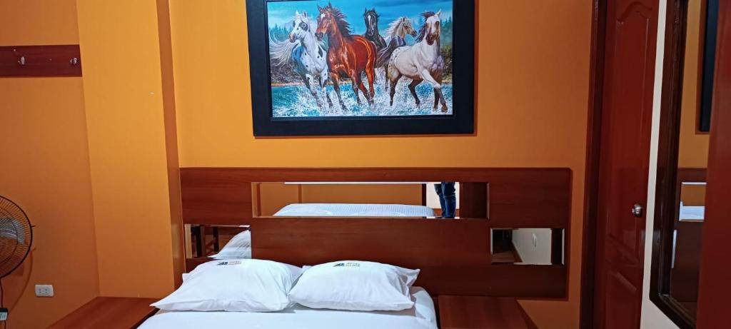 een slaapkamer met 2 bedden en een schilderij van paarden bij Hotel Allison in Huacho