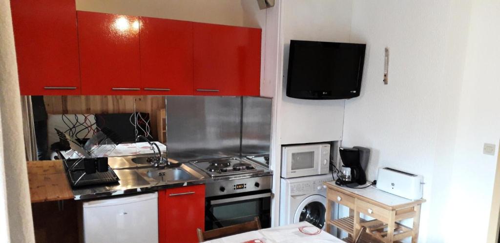 kuchnia z czerwonymi szafkami i piekarnikiem w obiekcie Résidence La Croix Du Sud - Studio pour 4 Personnes 24 w mieście Valloire