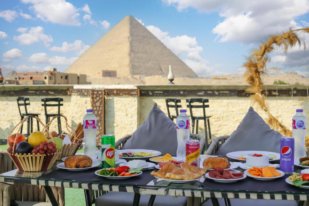 una tavola con cibo sopra con una piramide sullo sfondo di Master Pyramids Inn a Il Cairo