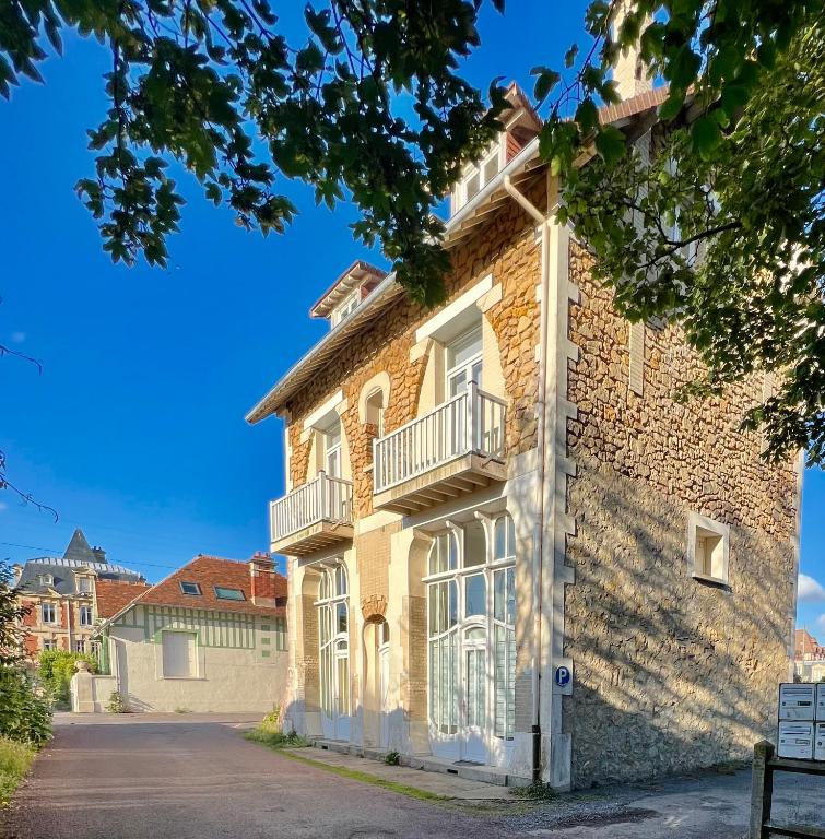 - un bâtiment en briques avec un balcon dans une rue dans l'établissement La sapinière, duplex de charme, à Hermanville-sur-Mer