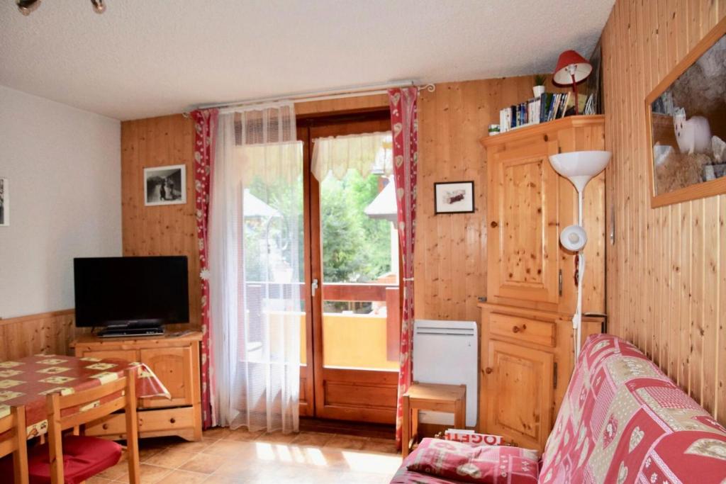 a living room with a table and a television and a window at Résidence La Demeurance - 2 Pièces pour 4 Personnes 34 in Valloire