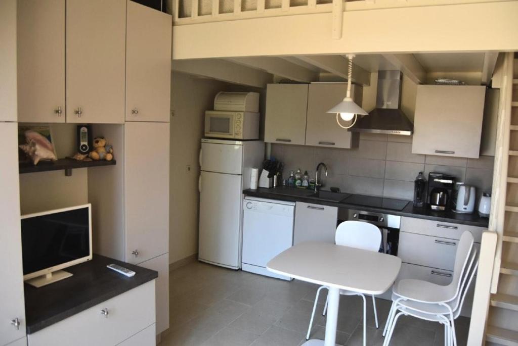 eine Küche mit weißen Geräten sowie einem Tisch und Stühlen in der Unterkunft Résidence LE HAMEAU DES PECHEURS - Maisons & Villas pour 4 Personnes 34 in Port Leucate