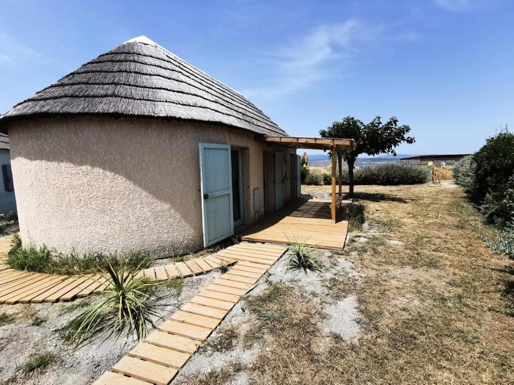 un petit bâtiment avec un toit de chaume et une passerelle en bois dans l'établissement Résidence Ile Des Pecheurs - VILLA 3 PIECES 6 couchages LE BARCARES MAE-4464, à Port-Leucate