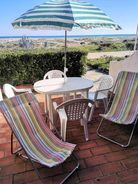 une table et des chaises avec un parasol sur une terrasse dans l'établissement Résidence Maisons De La Mer 2 - Confortable studio pour trois personnes face à la mer à Port Leucate. Réf: 1MM2_135 MAE-4724, à Port-Leucate