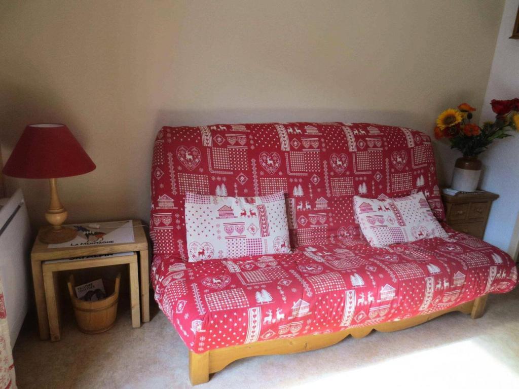a red couch in a room with a table with a lamp at Résidence Betelgeuse - Studio pour 4 Personnes 34 in Valloire