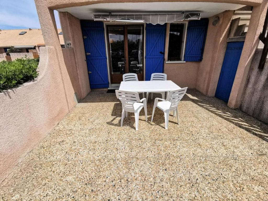 une table et des chaises blanches devant une maison dans l'établissement Résidence Grande Bleue - 2 Pièces 4 couchages PORT LEUCATE MAE-5264, à Port-Leucate