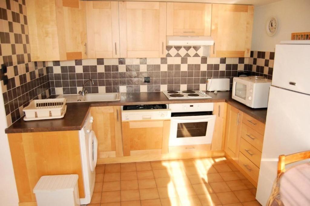 une cuisine avec des armoires en bois et un réfrigérateur blanc dans l'établissement Résidence Grande Bleue - VILLA 3 PIECES 6 couchages PORT LEUCATE MAE-5194, à Port-Leucate