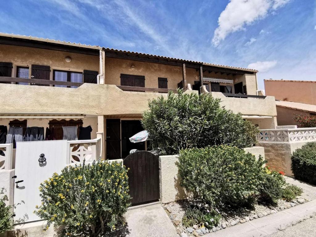 une maison avec un portail et des buissons devant elle dans l'établissement Résidence Grande Bleue - 2 Pièces 4 couchages PORT LEUCATE MAE-5344, à Port-Leucate