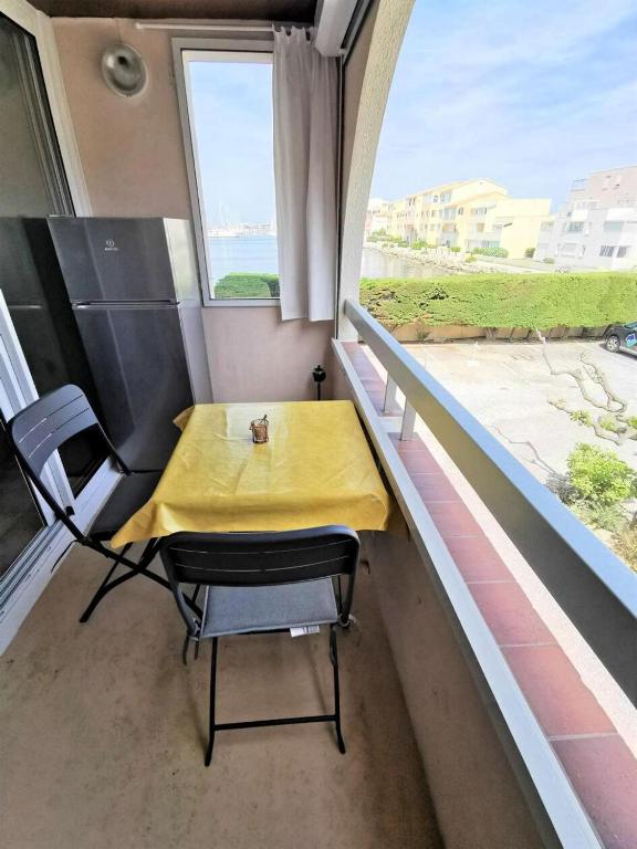 une table et des chaises dans une pièce avec une fenêtre dans l'établissement Résidence Terrasses De La Mediterranee 3 - APPT T2 CAB OU MEZZ 4 couchages PORT LEUCATE MAE-5434, à Port-Leucate