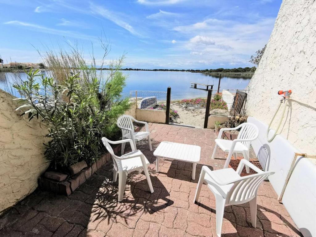 - un ensemble de chaises blanches assises sur une terrasse près de l'eau dans l'établissement Résidence Marina Plage - VILLA 3 PIECES 6 couchages PORT LEUCATE MAE-5644, à Port-Leucate