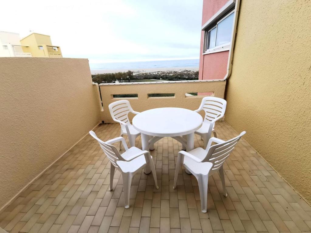 une table blanche et des chaises sur un balcon dans l'établissement Résidence Les Nefs Des Sables - APPT T2 CAB OU MEZZ 6 couchages PORT LEUCATE. Réf: 2NEF_33K3 MAE-5534, à Port-Leucate