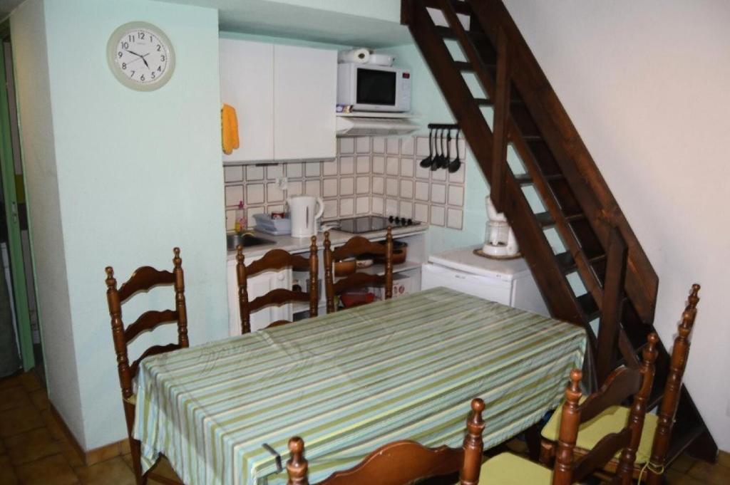 une cuisine avec une table et un escalier avec une horloge dans l'établissement Résidence Les Maisons Du Soleil - VILLA T2 MEZZANINE 4 couchages PORT LEUCATE MAE-5914, à Port-Leucate