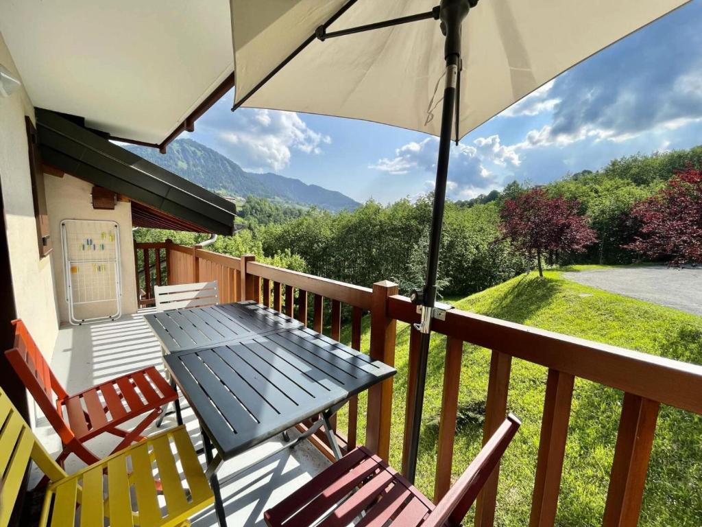 a table and chairs on a porch with an umbrella at Les Chalets Des Evettes - 3 Pièces pour 6 Personnes 44 in Notre-Dame-de-Bellecombe