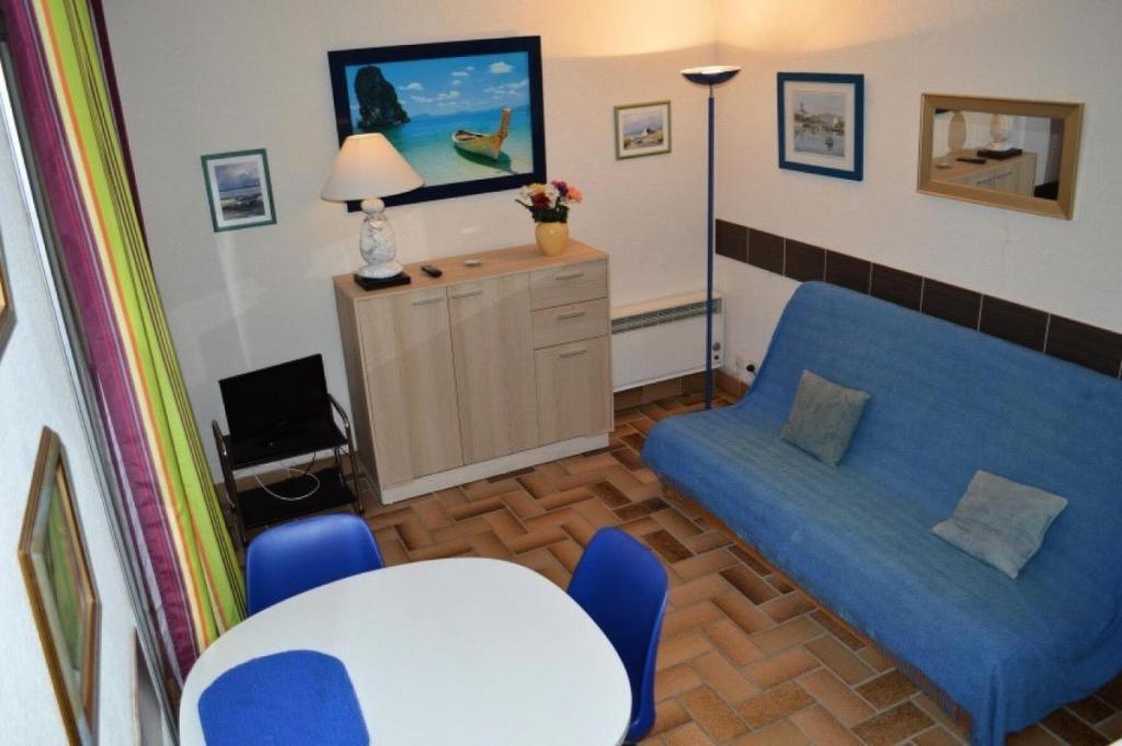 uma sala de estar com um sofá azul e uma mesa em Résidence LES CYCLADES - Studio pour 2 Personnes 54 em Port Leucate