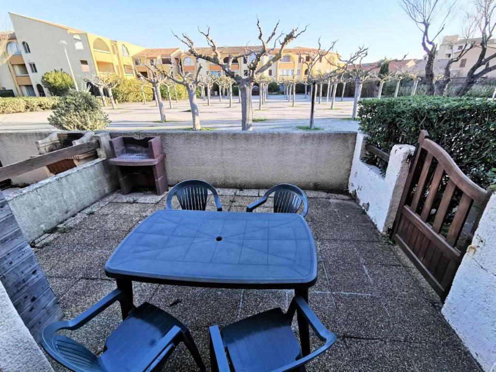 uma mesa azul com duas cadeiras e um banco em Résidence MAISONS DE LA PLAGE - Maisons & Villas pour 6 Personnes 074 em Port Leucate