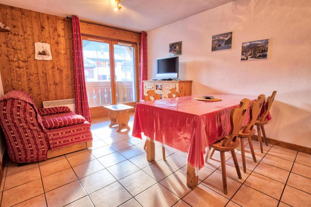 ein Wohnzimmer mit einem Tisch, Stühlen und einem TV in der Unterkunft Résidence Les Oursons - 2 Pièces pour 6 Personnes 34 in Notre-Dame-de-Bellecombe