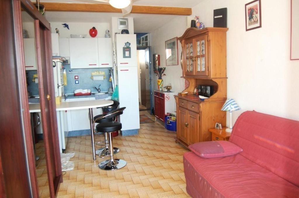 un salon avec un canapé rouge et une cuisine dans l'établissement Résidence Karukera - STUDIO 2 PERSONNES 3 couchages PORT LEUCATE MAE-6424, à Port-Leucate