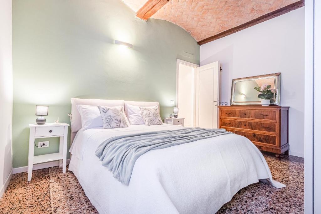 a bedroom with a white bed and a dresser at Ghirlandina - La casa dell'Esteta in Modena