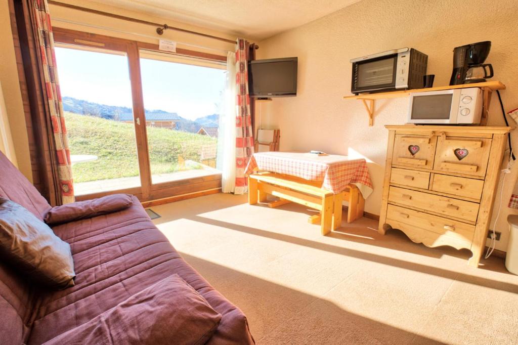 a living room with a couch and a tv and a window at Résidence Le Chambet - Studio calme avec jardin MAE-3354 in Notre-Dame-de-Bellecombe