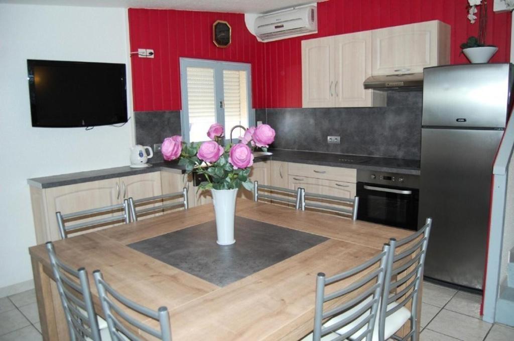une cuisine avec une table et un vase de roses roses roses dans l'établissement Résidence Rue De La Jonquiere - 4 Pièces 8 couchages PORT LEUCATE MAE-7484, à Port-Leucate