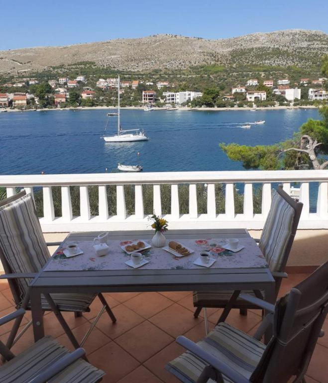ein Tisch auf einem Balkon mit einem Boot im Wasser in der Unterkunft Lumare in Grebaštica