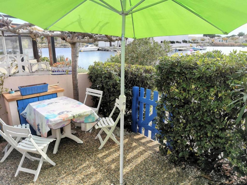 une table et des chaises avec un parasol vert dans l'établissement Résidence Les Barcarelles - VILLA T2 CABINE 4 couchages LE BARCARES MAE-1334, à Port-Leucate