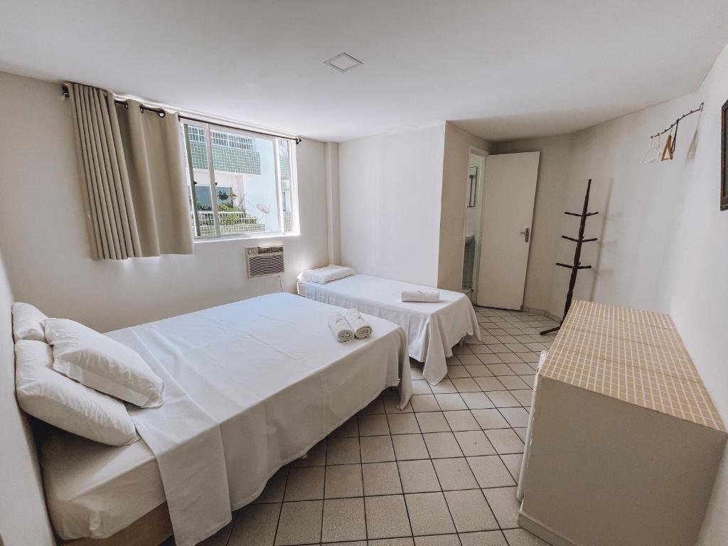 a bedroom with two beds and a window at Hotel América Praia in Recife